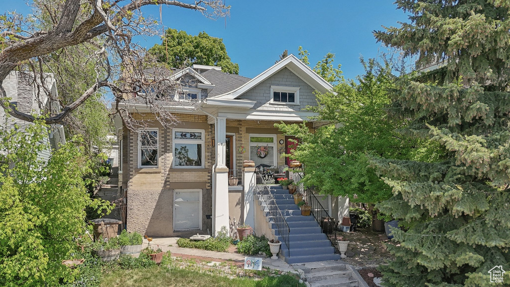 View of front of house with stairway, covered porch, and brick siding