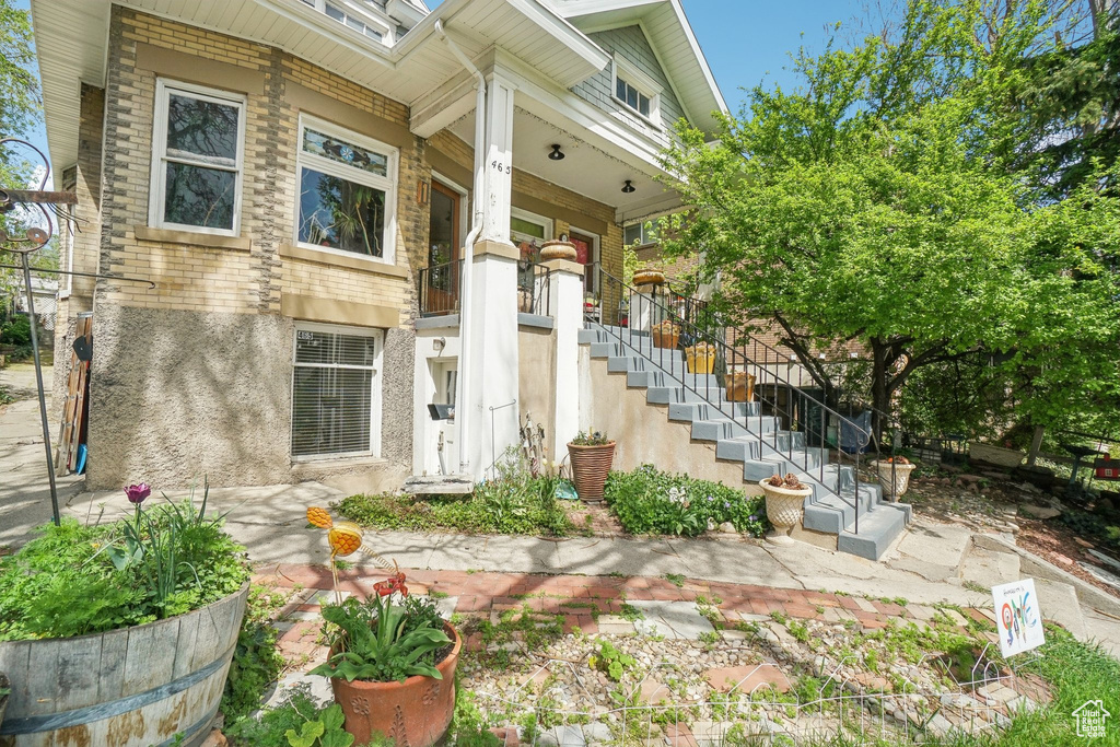 Doorway to property featuring covered porch and stucco siding