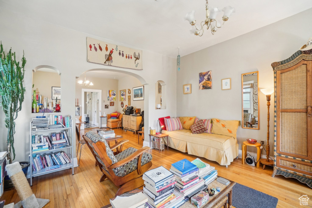 Living room featuring a chandelier, arched walkways, and light wood-type flooring