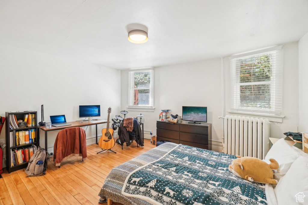 Bedroom featuring radiator, hardwood / wood-style flooring, baseboard heating, and baseboards