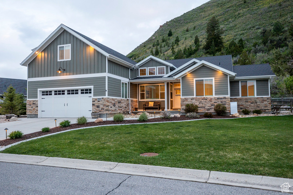 Craftsman inspired home featuring a porch, board and batten siding, stone siding, and a front yard