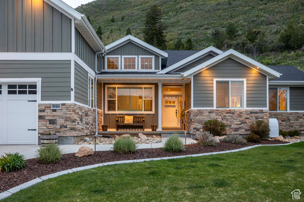 View of front of house with stone siding, board and batten siding, covered porch, and a garage