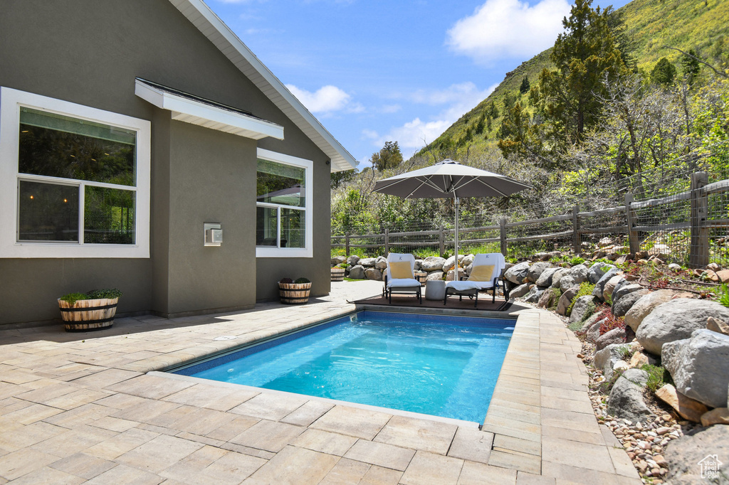 View of pool with a patio area, fence, and a mountain view
