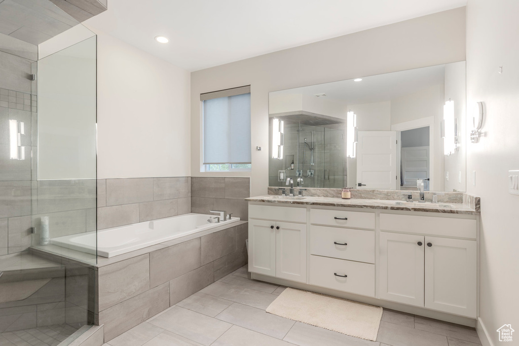 Bathroom featuring a shower stall, a bath, double vanity, recessed lighting, and tile patterned flooring