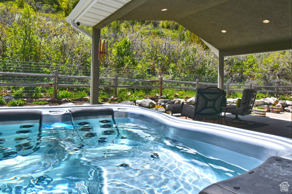 View of pool with a hot tub, a fenced backyard, and a deck