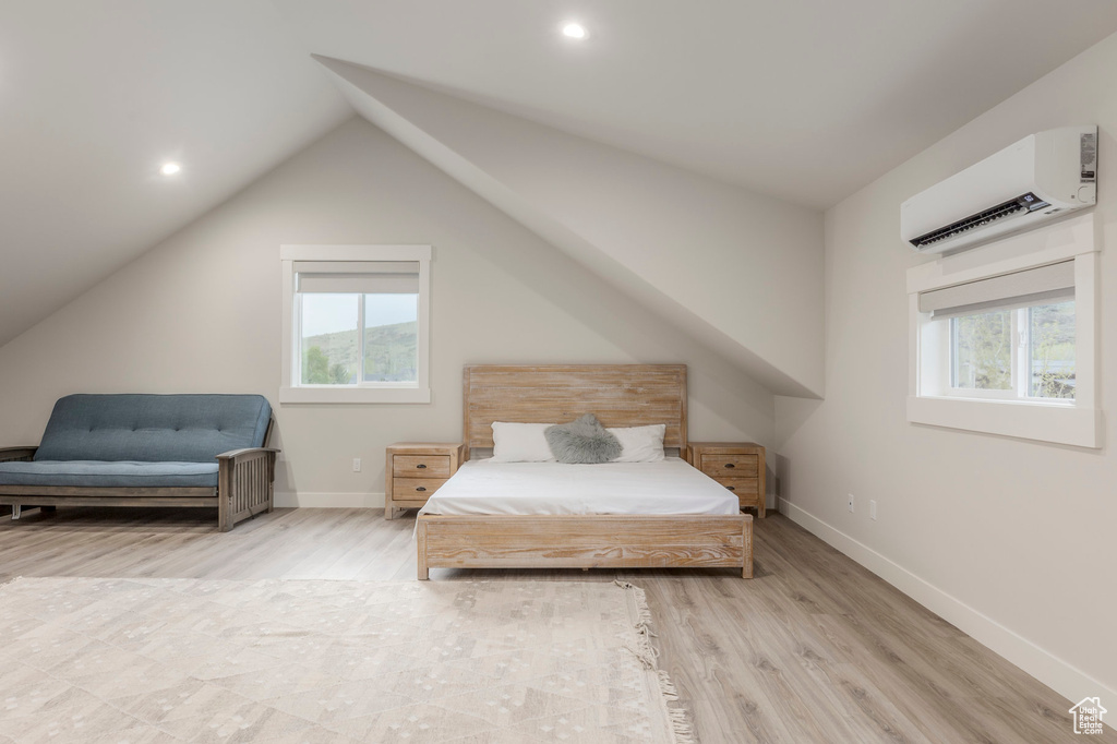 Bedroom featuring a wall unit AC, light wood-style flooring, baseboards, vaulted ceiling, and recessed lighting