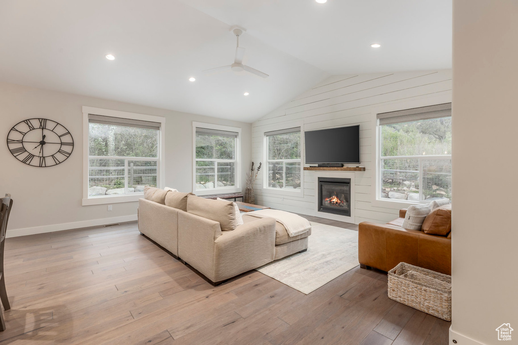 Living area with a ceiling fan, a fireplace, wood finished floors, lofted ceiling, and recessed lighting