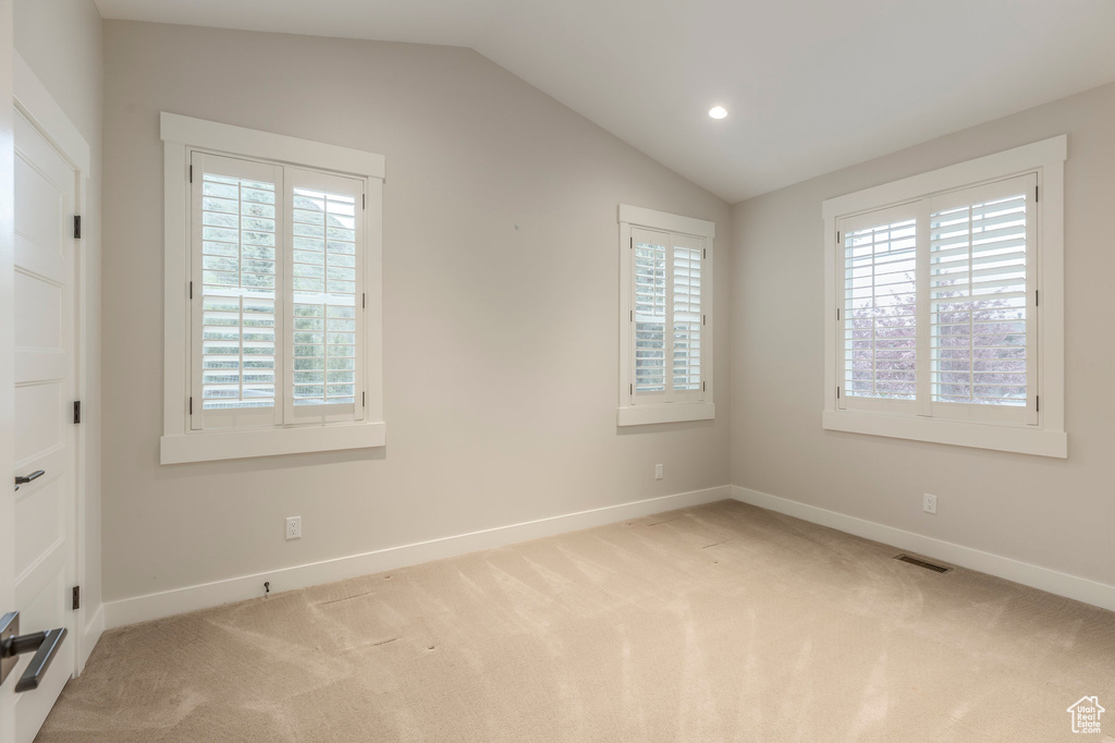 Carpeted spare room featuring healthy amount of natural light, baseboards, vaulted ceiling, and recessed lighting