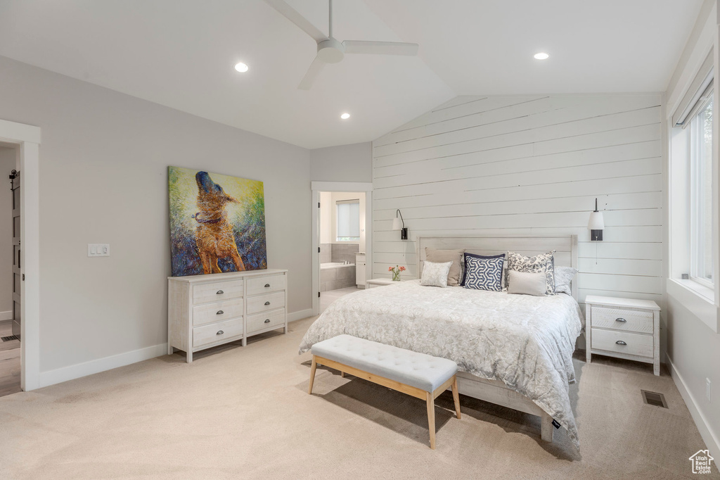 Bedroom with vaulted ceiling, light colored carpet, baseboards, recessed lighting, and ensuite bathroom