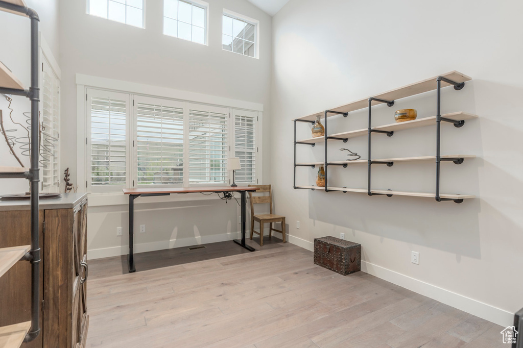 Interior space featuring light wood-style floors, baseboards, and a towering ceiling