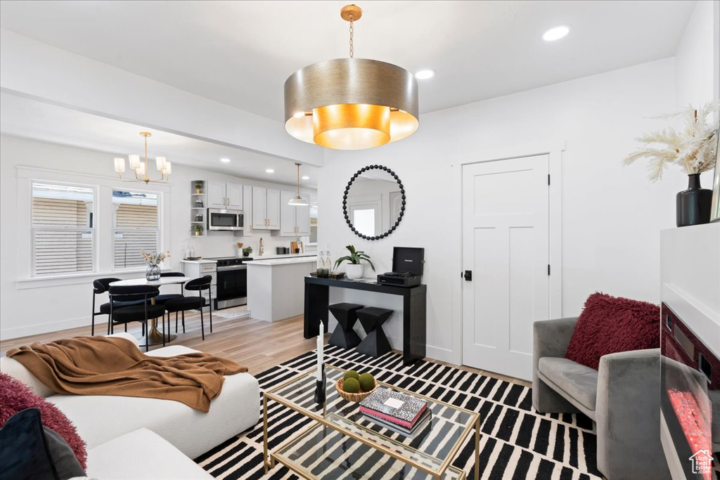Living area featuring a chandelier, light wood-style floors, recessed lighting, and baseboards