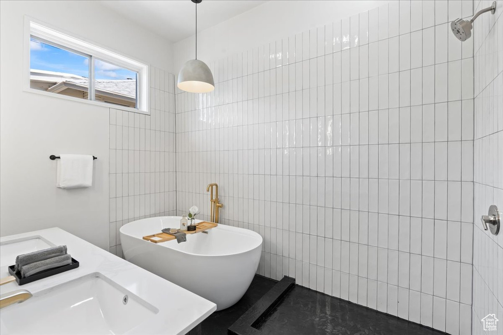 Full bathroom with tile walls, a freestanding tub, tiled shower, and a sink