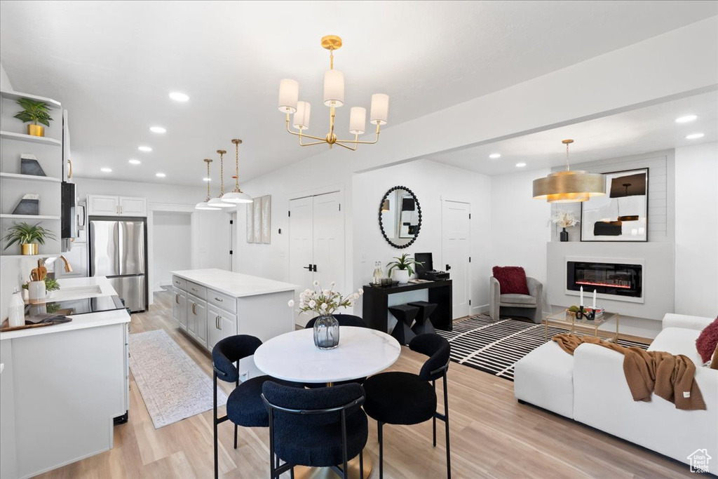 Dining room featuring light wood-style floors, recessed lighting, a large fireplace, and a chandelier