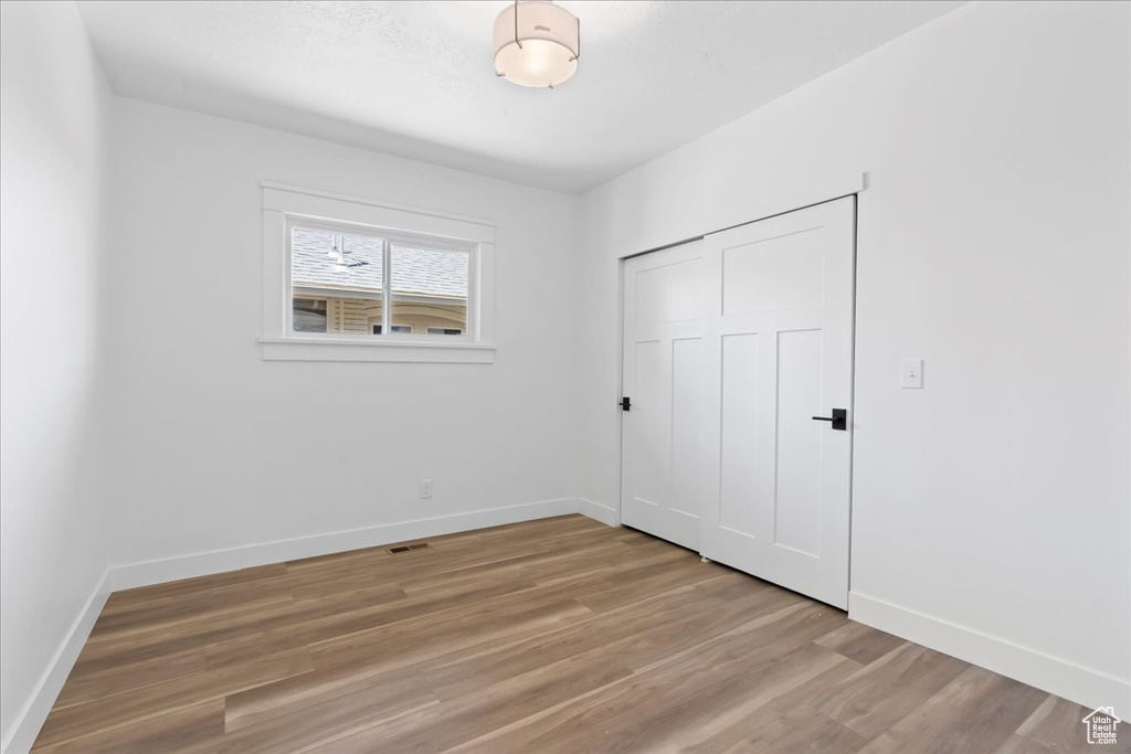 Unfurnished bedroom featuring baseboards, light wood finished floors, and a closet