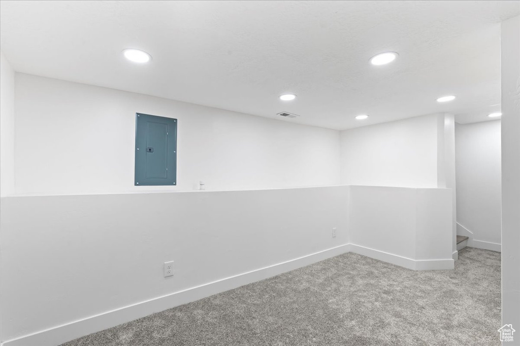 Carpeted empty room featuring electric panel, recessed lighting, and baseboards