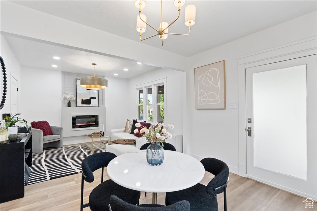 Dining space with recessed lighting, light wood-style floors, a glass covered fireplace, and a chandelier