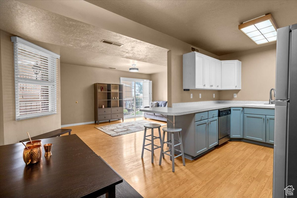 Kitchen with stainless steel appliances, a sink, a peninsula, light wood-style floors, and a breakfast bar area