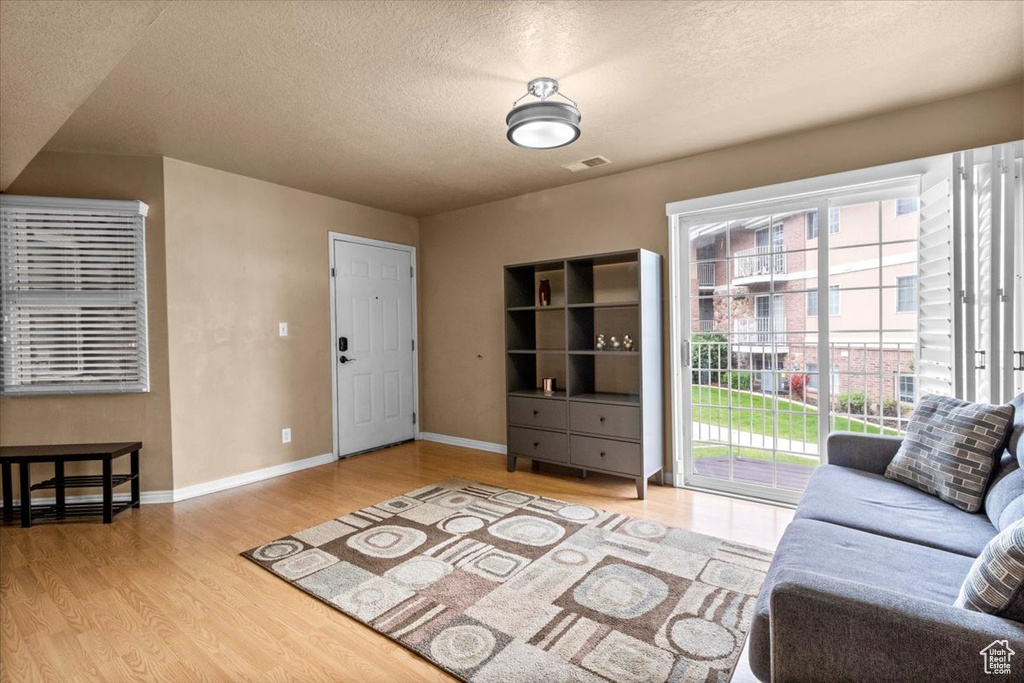 Living room with a textured ceiling, wood finished floors, and baseboards