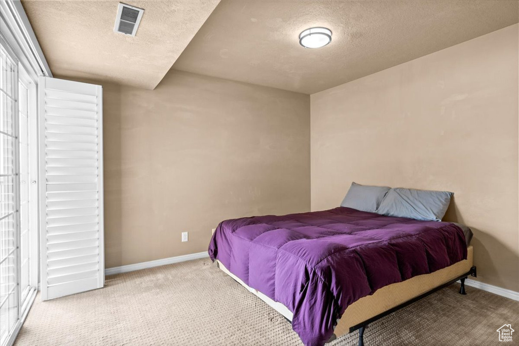 Carpeted bedroom featuring a textured ceiling and baseboards
