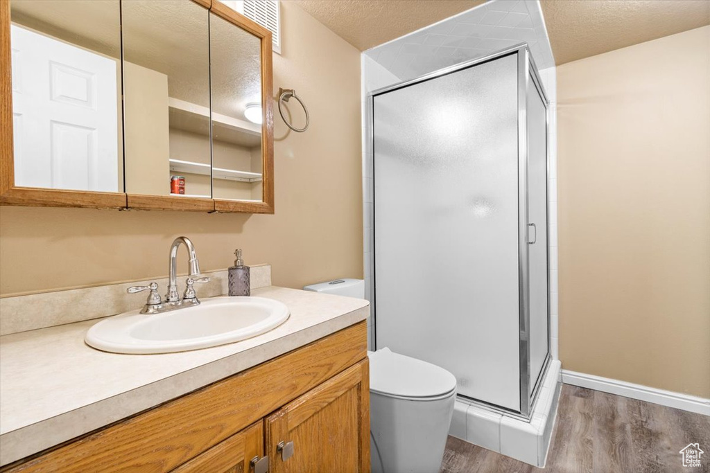 Bathroom with wood finished floors, toilet, a shower stall, and vanity