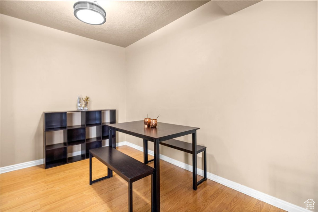 Dining space with wood finished floors, baseboards, and a textured ceiling