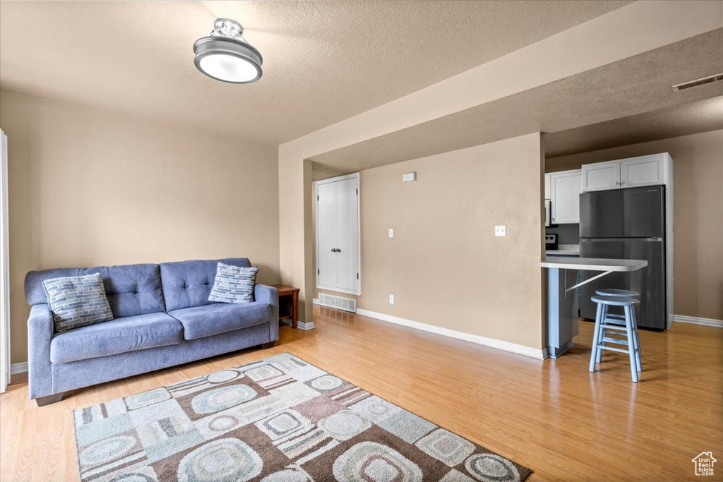 Living room featuring light wood-type flooring, baseboards, and a textured ceiling