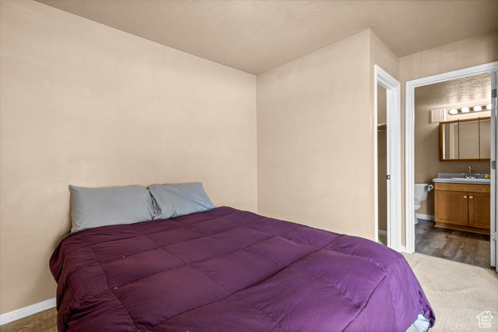 Carpeted bedroom with a sink, baseboards, and connected bathroom