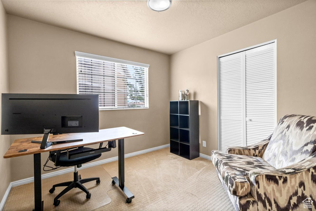 Carpeted home office featuring baseboards