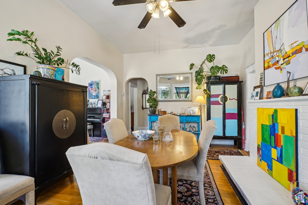Dining room with ceiling fan, arched walkways, and wood finished floors