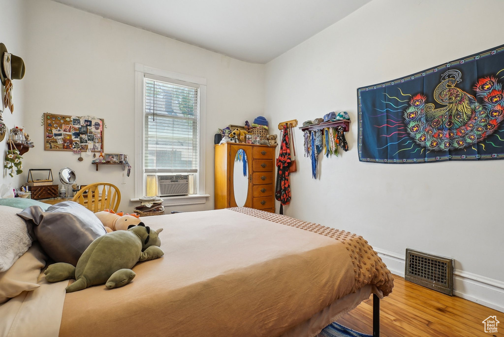 Bedroom featuring wood finished floors, cooling unit, and baseboards