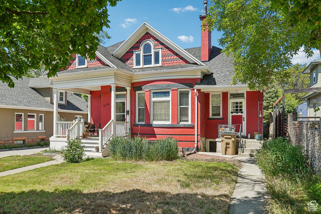 Victorian house featuring a porch and a chimney