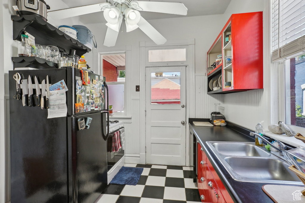 Kitchen with freestanding refrigerator, a sink, tile patterned floors, and plenty of natural light