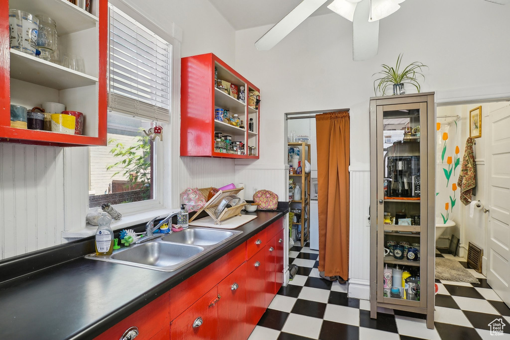 Kitchen with tile patterned floors, red cabinetry, a sink, and dark countertops