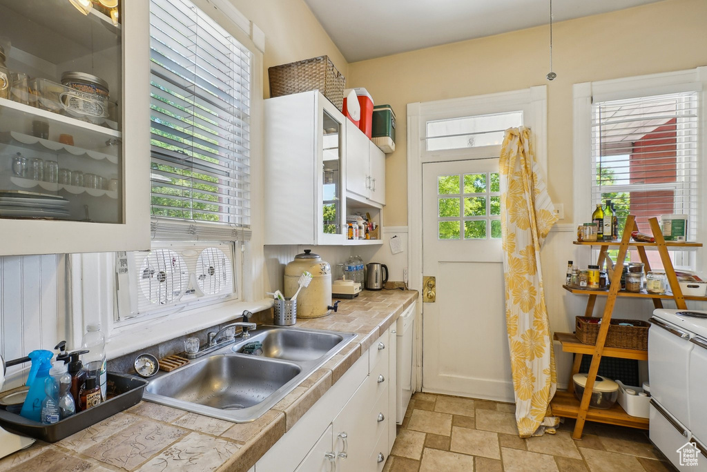 Kitchen featuring a sink, stone finish flooring, range, and white cabinetry