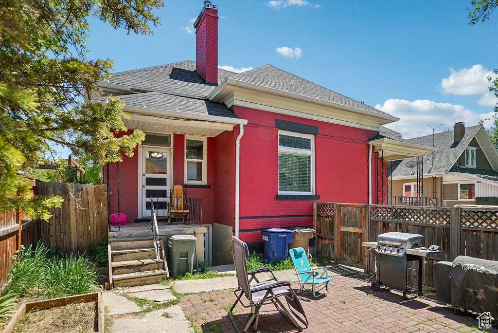 Back of property featuring roof with shingles, a chimney, and a patio area