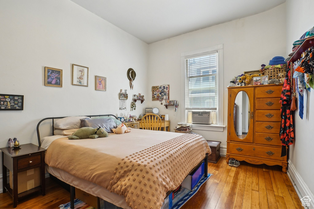 Bedroom with cooling unit, hardwood / wood-style floors, and baseboards
