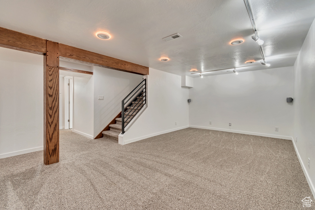 Finished below grade area with carpet flooring, baseboards, and stairway
