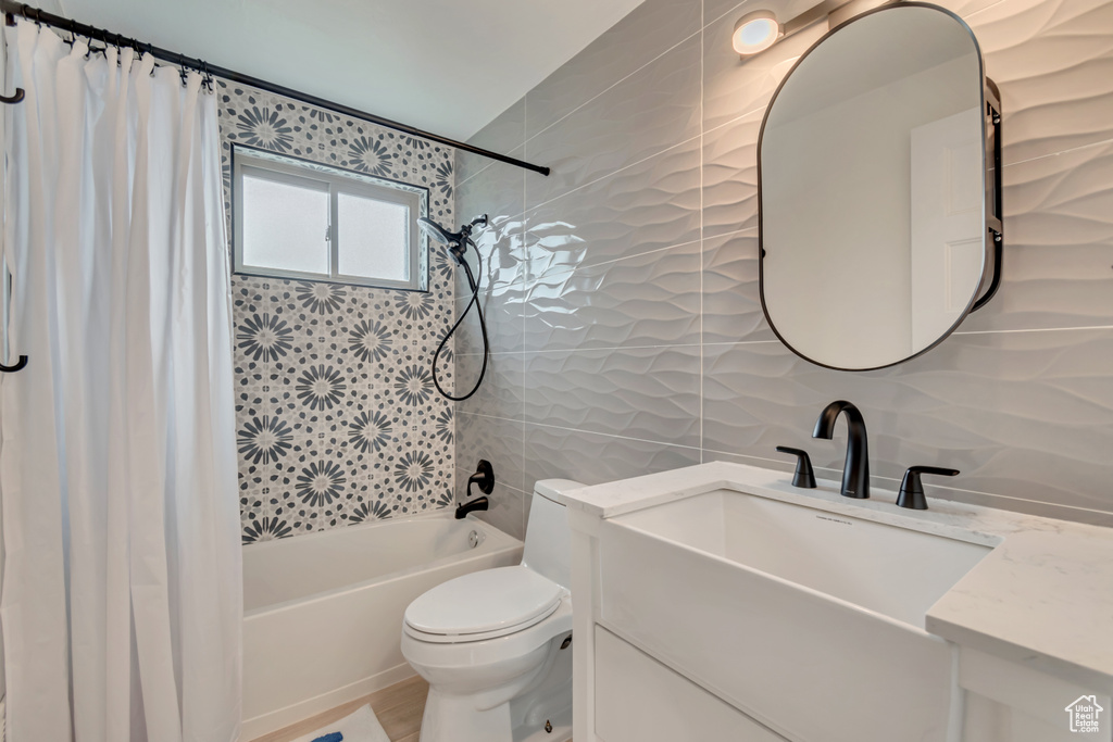 Full bath featuring shower / tub combo with curtain, vanity, toilet, tile walls, and backsplash