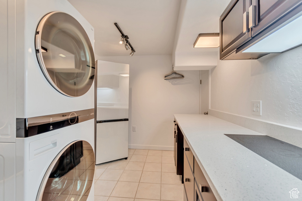 Laundry area with stacked washer / dryer and light tile patterned flooring