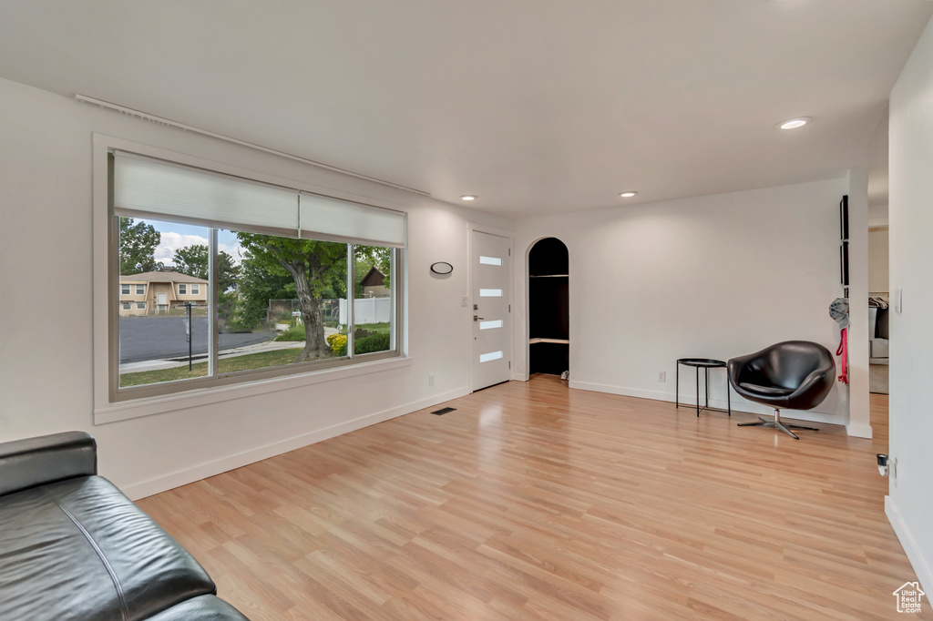 Unfurnished living room with arched walkways, light wood-type flooring, recessed lighting, and baseboards