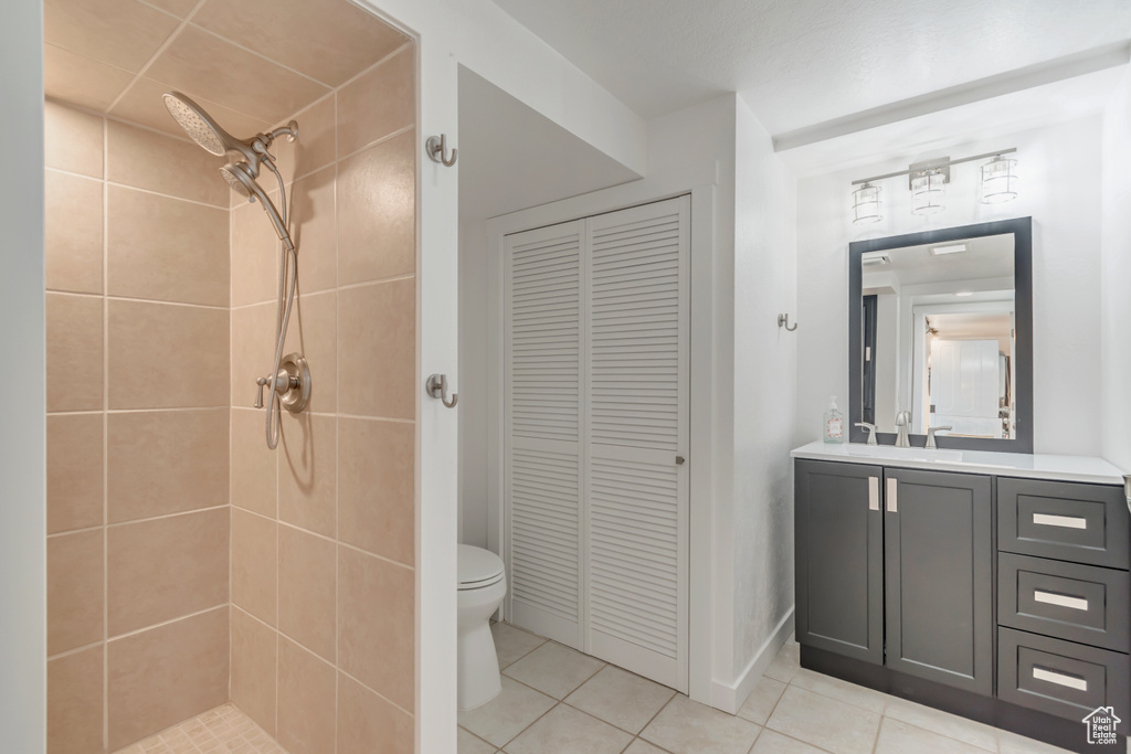 Bathroom with tile patterned flooring, tiled shower, toilet, a closet, and vanity