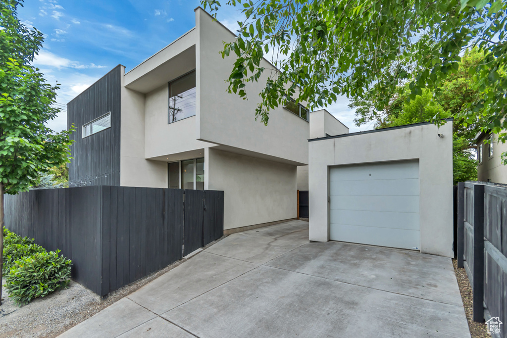 Contemporary home with concrete driveway, fence, stucco siding, and a garage