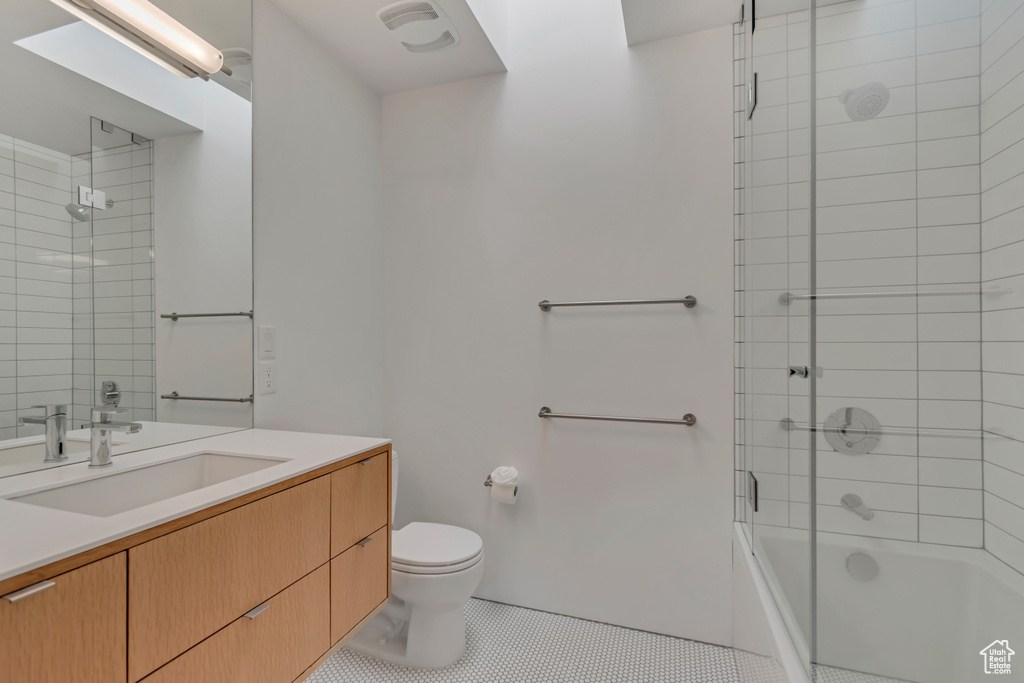 Bathroom featuring tile patterned flooring, toilet, combined bath / shower with glass door, and vanity