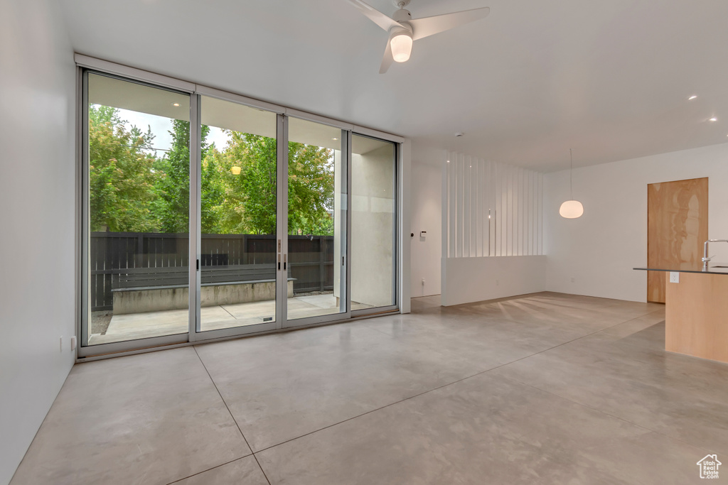 Empty room featuring concrete flooring, expansive windows, healthy amount of natural light, and ceiling fan