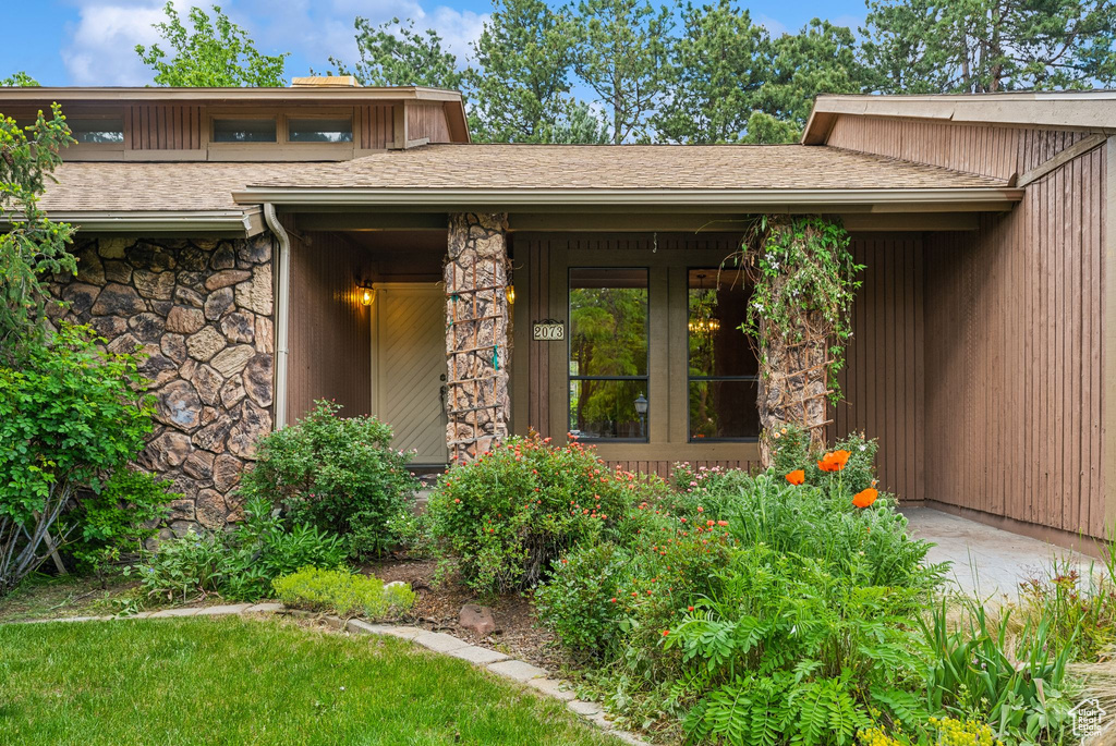Property entrance featuring stone siding and roof with shingles