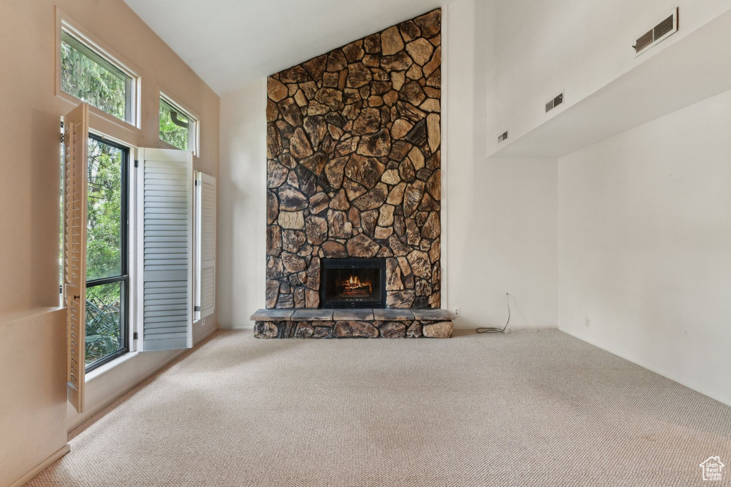Unfurnished living room featuring carpet flooring, a fireplace, and high vaulted ceiling
