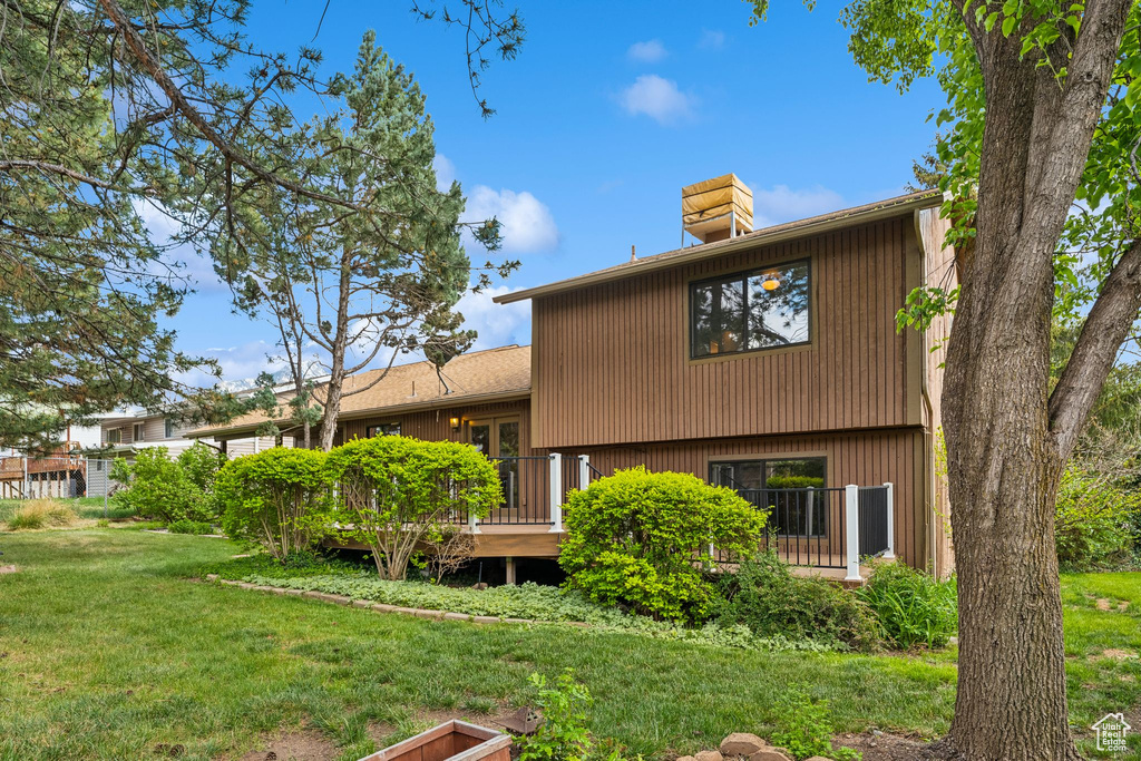 Back of property with a yard, a chimney, and a deck