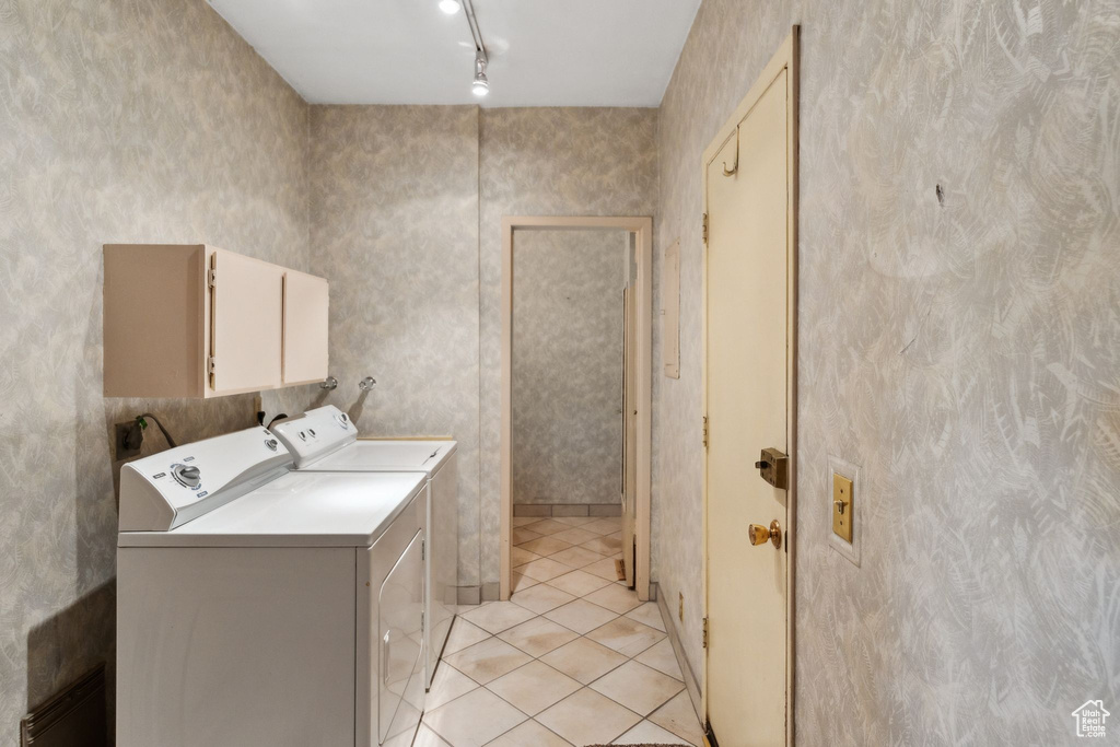 Washroom featuring separate washer and dryer, cabinet space, light tile patterned floors, and track lighting
