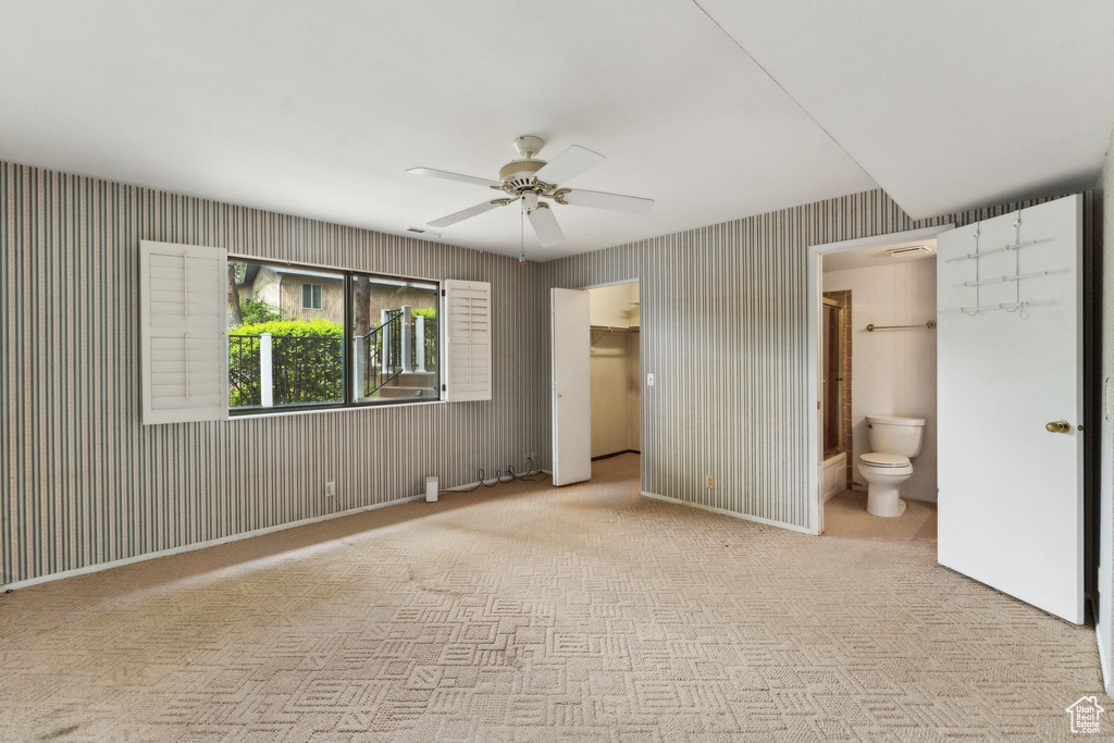 Unfurnished bedroom featuring carpet flooring, connected bathroom, a closet, a ceiling fan, and a walk in closet