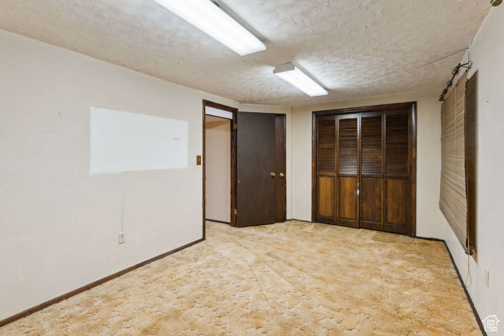 Spare room with a textured ceiling, carpet, and baseboards